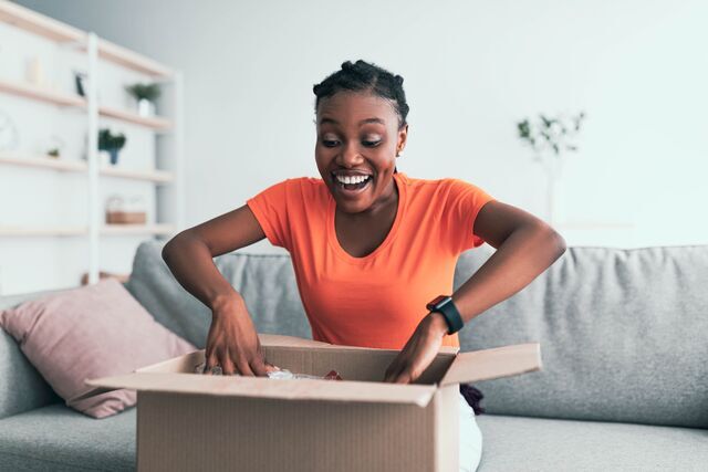 small-SINGLE-IMAGE_excited-black-woman-opening-package-at-home-full-colour_july25